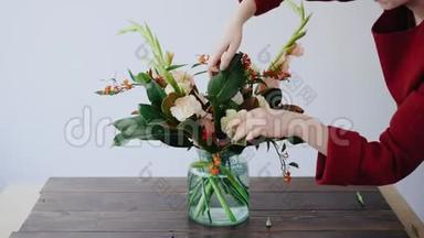 女花匠把花放在玻璃花瓶里，做了一个新的花安排。 从<strong>盒子</strong>里摘<strong>鲜花</strong>的女人
